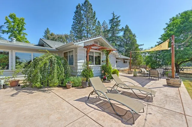 a view of a patio with table and chairs potted plants and floor to ceiling window and potted plants