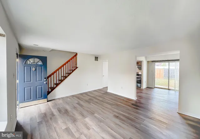 a view of an empty room with wooden floor and stairs