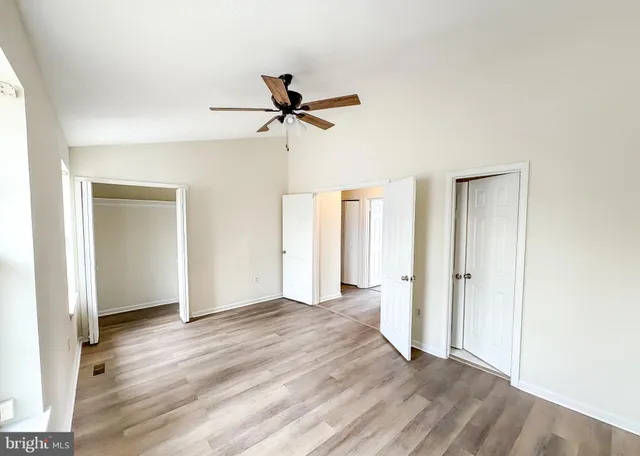 a view of empty room with wooden floor and ceiling fan