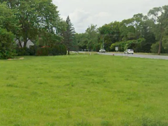 a view of a green field with wooden fence
