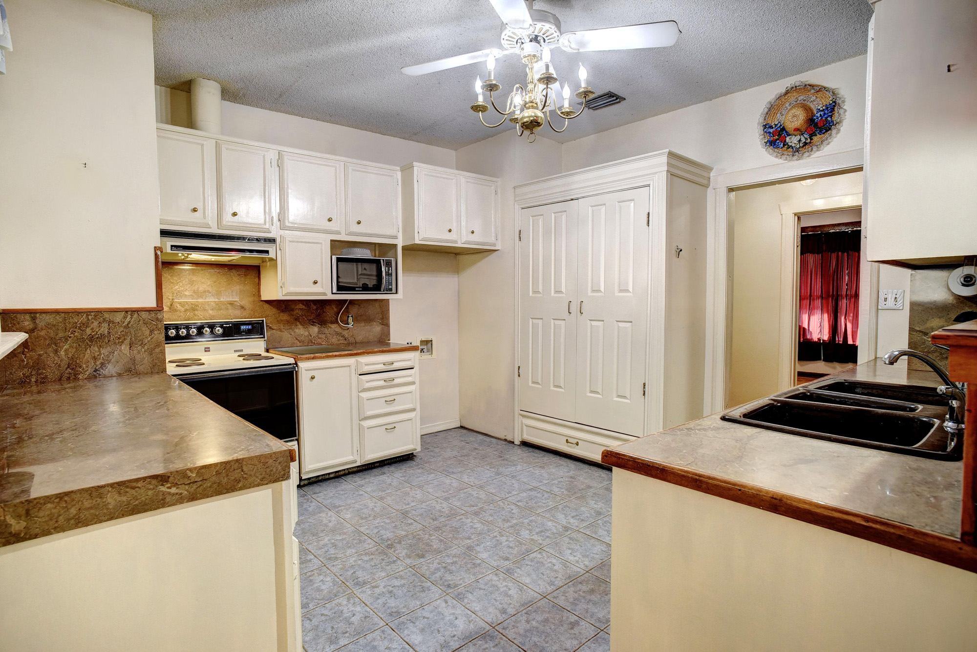 113 My Road Bastrop, TX 78602 - Photo 14 of 35 Kitchen with white range with electric cooktop, a textured ceiling, white cabinetry, stainless steel microwave, and under cabinet range hood