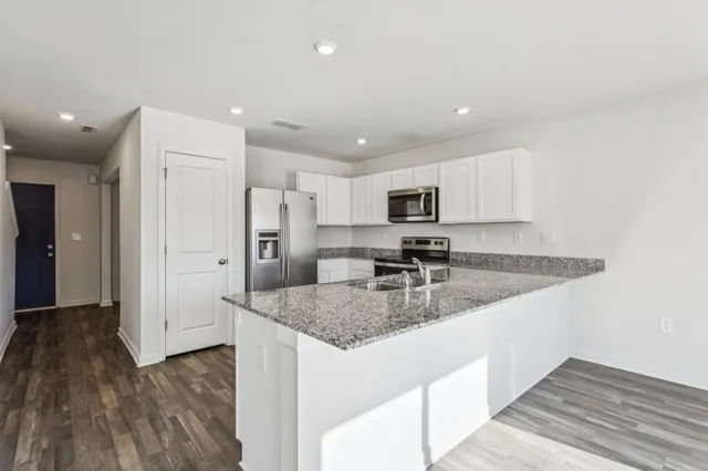 a kitchen with stainless steel appliances granite countertop a lot of counter space and wooden floors
