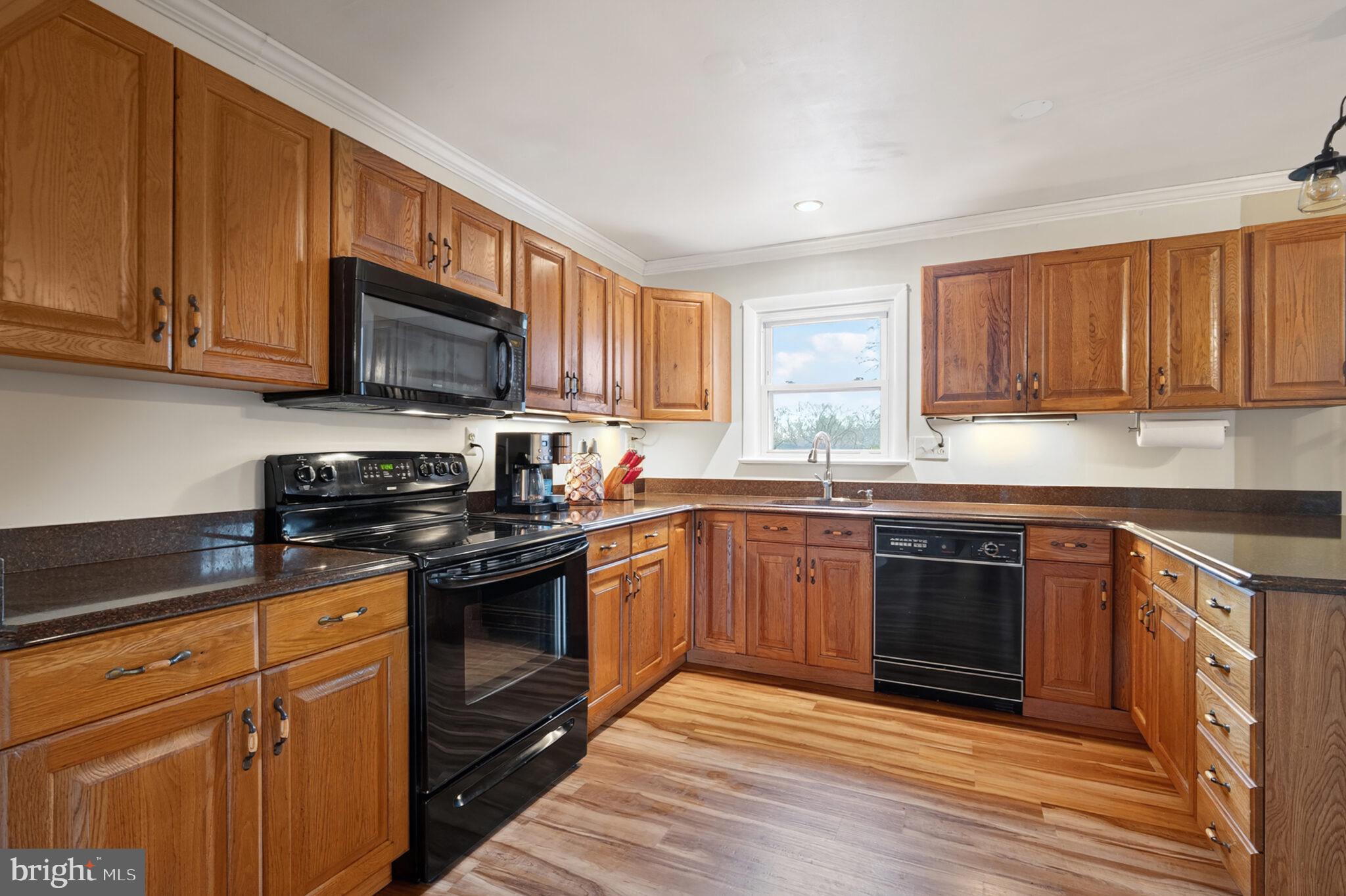 7507 Dover Lane Hyattsville, MD 20784 - Photo 10 of 53 a kitchen with stainless steel appliances granite countertop a stove a sink dishwasher and a microwave oven with wooden cabinets