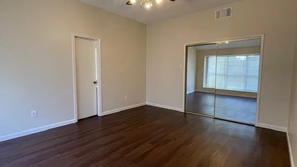 an empty room with wooden floor and windows