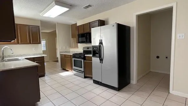 a kitchen with a refrigerator sink and cabinets