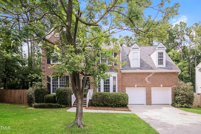 a front view of a house with a yard and a tree