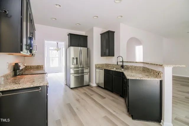 a large kitchen with granite countertop a refrigerator and a sink
