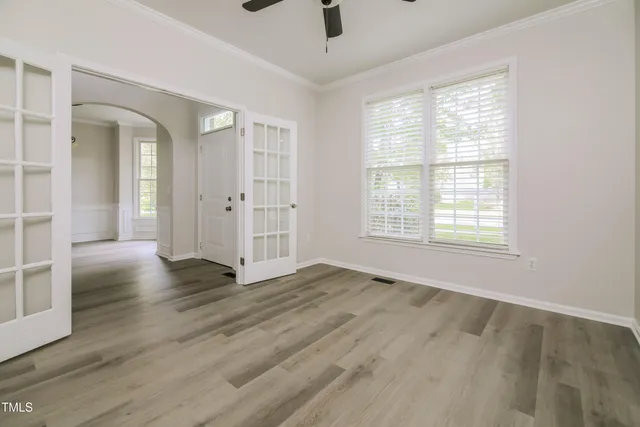 a view of an empty room with wooden floor and a window