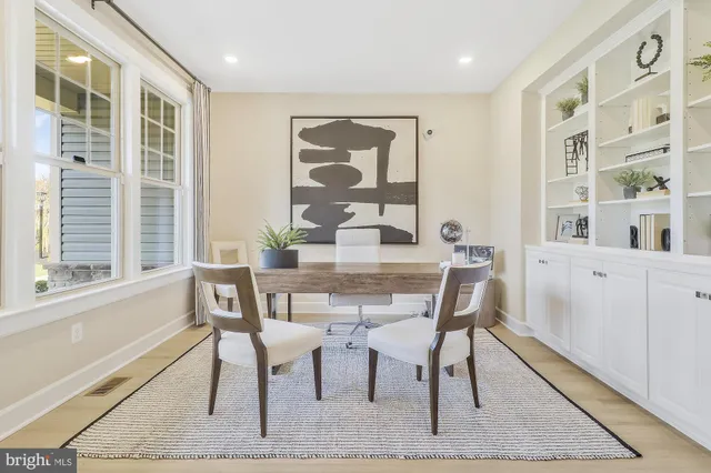 a dining room with wooden floor and large windows
