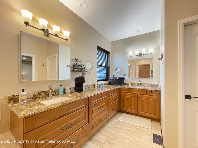 a spacious bedroom with a bed a dresser and a chandelier