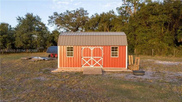 a view of a barn with a yard and a large tree