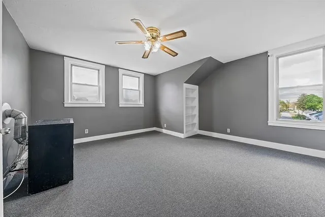 a view of an empty room with window and ceiling fan