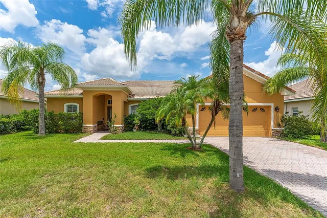 a view of yellow house with a yard and palm trees