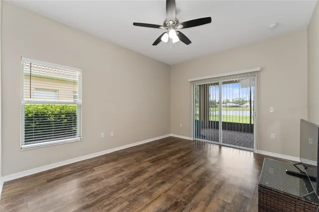 a view of empty room with wooden floor and fan