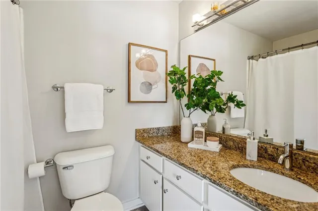 a bathroom with a granite countertop toilet sink and mirror