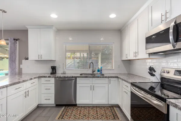 a kitchen with stainless steel appliances a sink a stove a microwave and cabinets