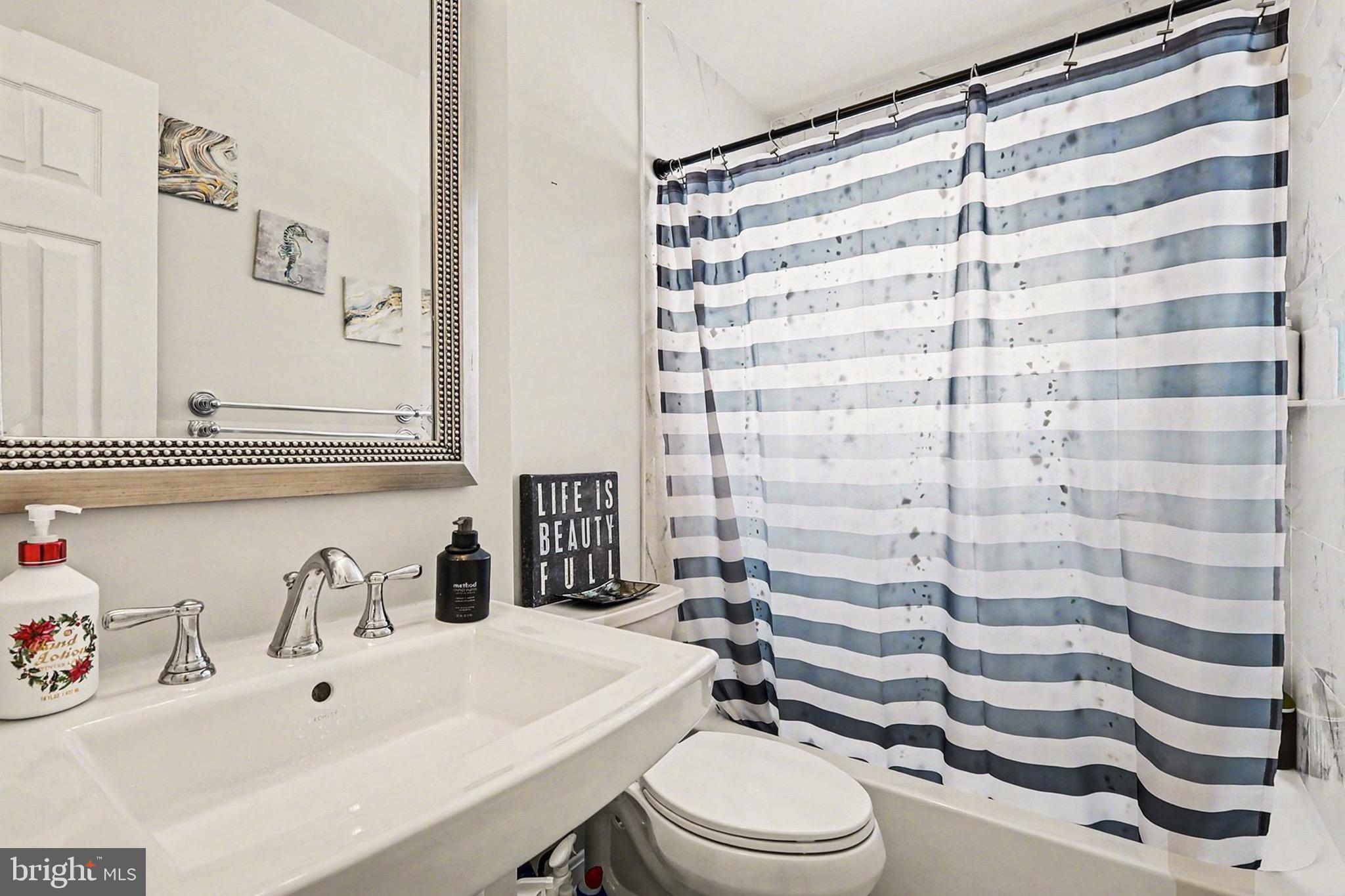 7112 Dalhouse Street Springfield, VA 22151 - Photo 14 of 25 a bathroom with a sink a toilet and shower curtain
