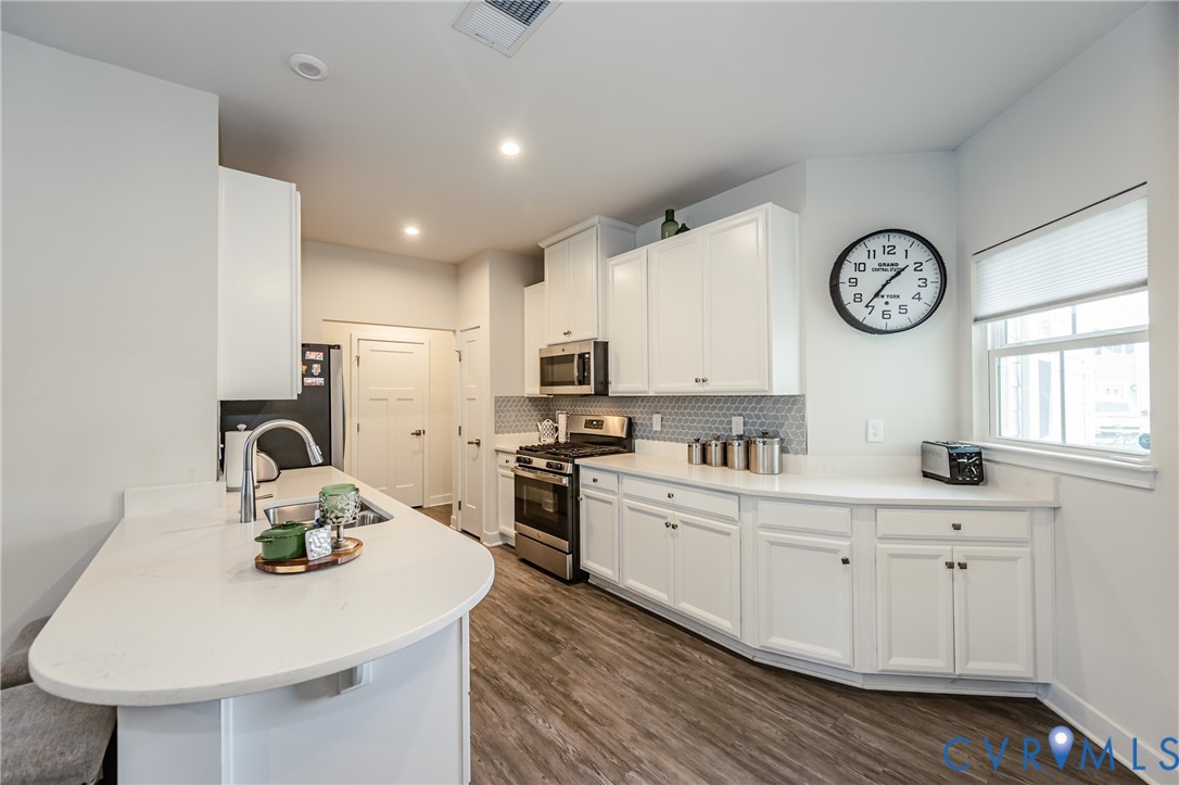 9073 Spring Green Loop Mechanicsville, VA 23116 - Photo 9 of 31 a kitchen with furniture a clock and cabinets