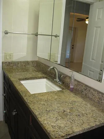 a bathroom with a granite countertop sink and a mirror