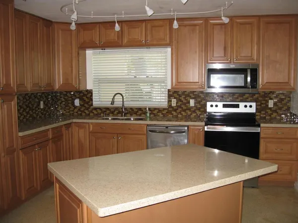 a kitchen with stainless steel appliances a sink a stove a microwave a refrigerator and cabinets