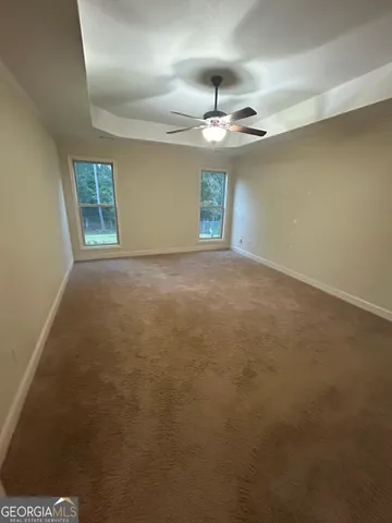 en empty room with windows and ceiling fan