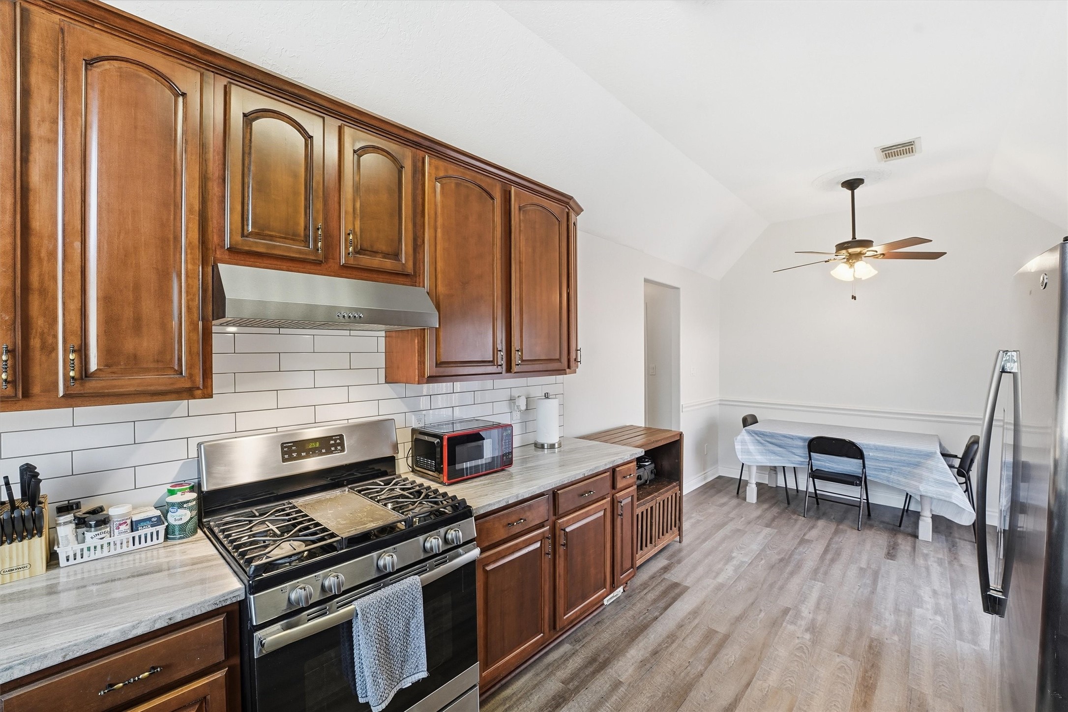 14103 Smith Road Humble, TX 77396 - Photo 9 of 39 a kitchen with granite countertop a stove a sink dishwasher and cabinets with wooden floor