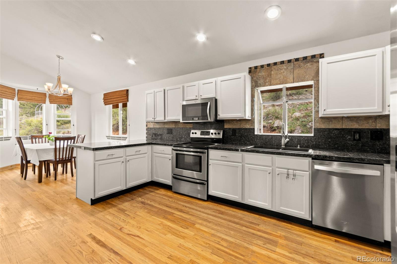 202 Badger Lane Bailey, CO 80421 - Photo 7 of 50 a kitchen with stainless steel appliances granite countertop a stove a sink a microwave a dining table and chairs