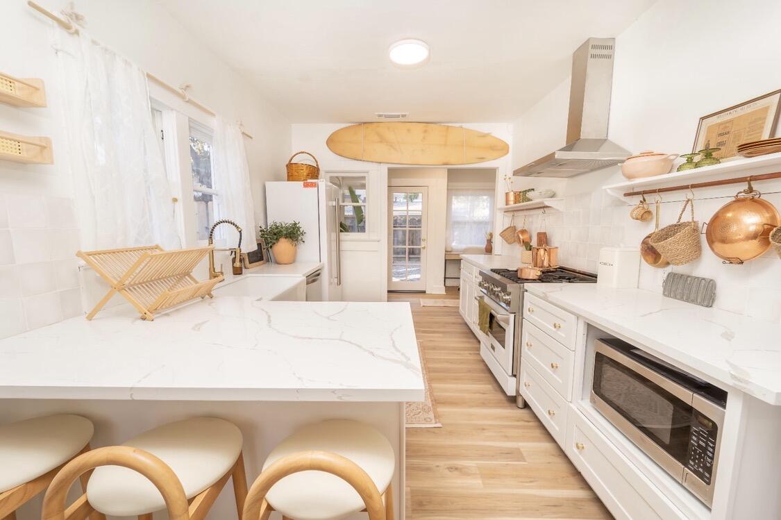 232 Ash Street Exeter, CA 93221 - Photo 7 of 13 a large white kitchen with a stove a sink and a wooden floor
