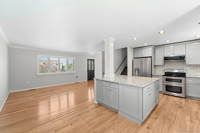 a large white kitchen with stainless steel appliances granite countertop a stove and a sink