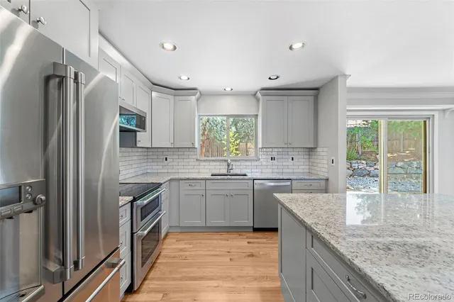 a kitchen with granite countertop a sink stove and refrigerator