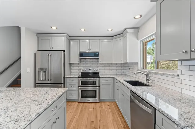 a kitchen with stainless steel appliances granite countertop a sink stove microwave and refrigerator