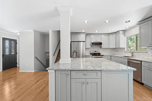 a kitchen with stainless steel appliances granite countertop a sink refrigerator and cabinets