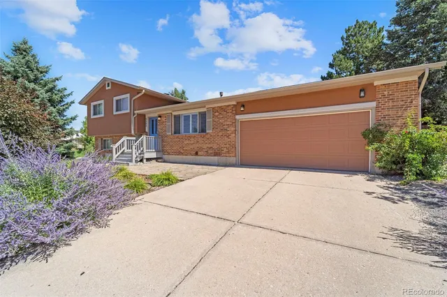 a front view of a house with a yard and potted plants