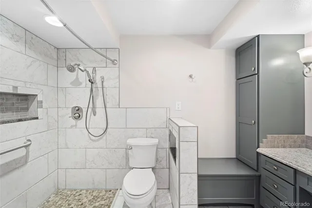 a bathroom with a granite countertop shower a toilet and sink