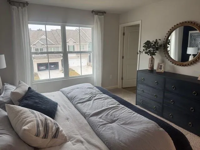 a bedroom with a bed a mirror on dresser and a window