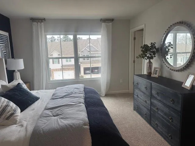 a bedroom with a bed a mirror on dresser and a window