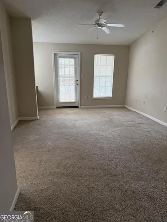 an empty room with windows and chandelier fan