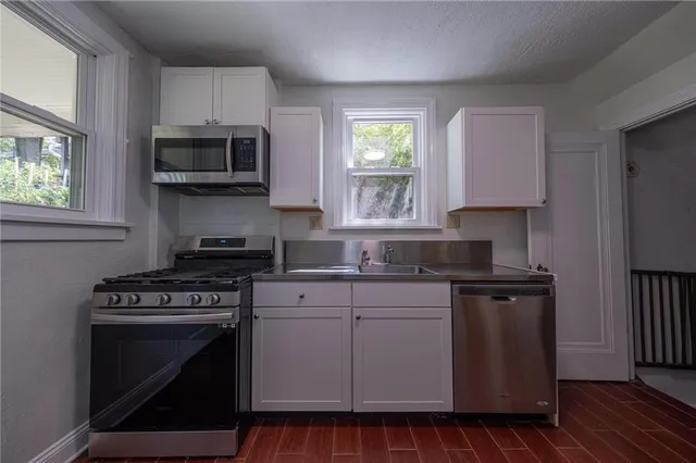 a kitchen with cabinets appliances a sink and a window
