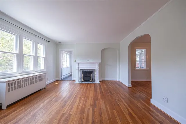 wooden floor fireplace and windows in an empty room