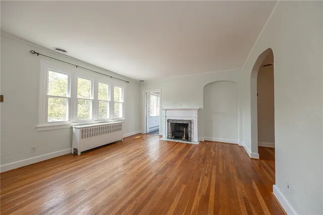 a view of empty room with wooden floor and fireplace