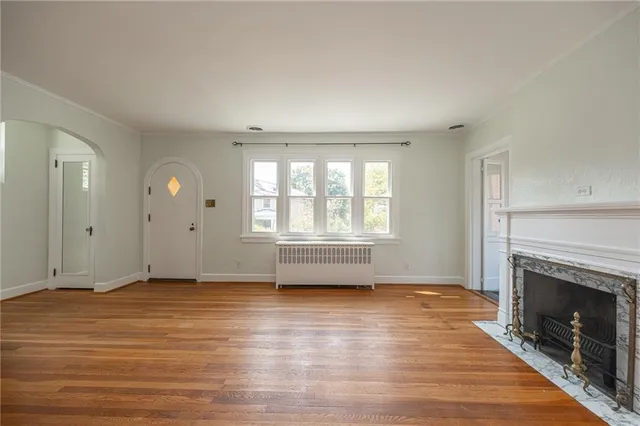 an empty room with wooden floor fireplace and windows