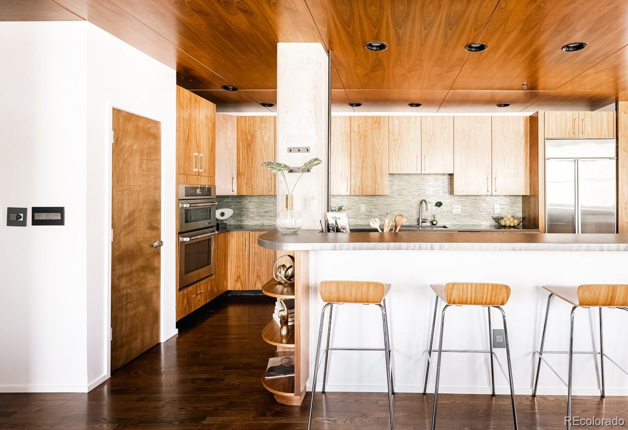1735 19th Street, Unit 4A Denver, CO 80202 - Photo 13 of 25 a open kitchen with granite countertop a stove top oven a sink and white cabinets with wooden floor