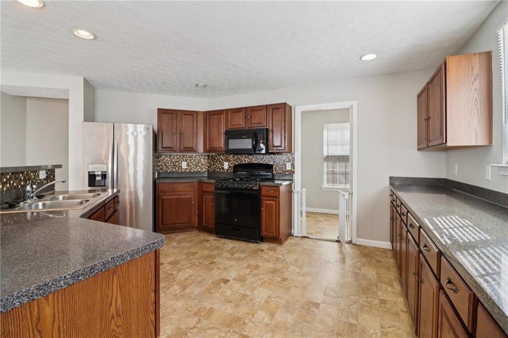 3118 Farmstead Court Grayson, GA 30017 - Photo 19 of 55 a kitchen with stainless steel appliances granite countertop a stove a sink and a refrigerator