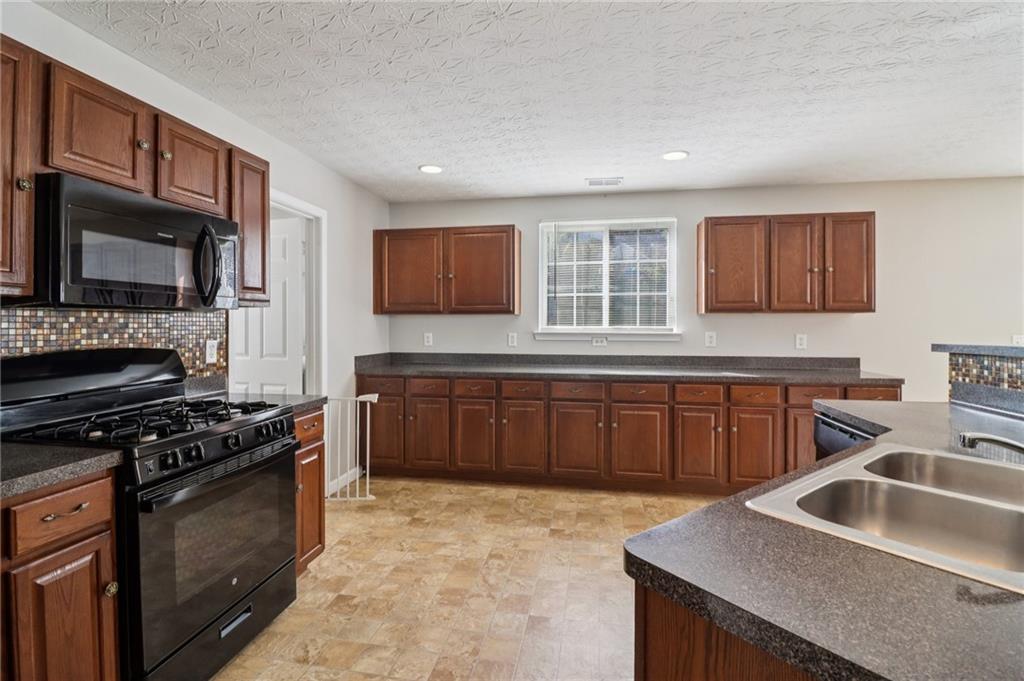 3118 Farmstead Court Grayson, GA 30017 - Photo 21 of 55 a kitchen with granite countertop a stove sink and microwave