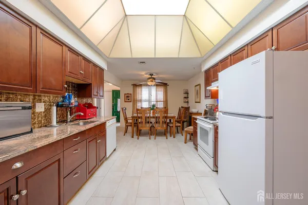 a kitchen with a refrigerator a sink dishwasher a dining table and chairs with wooden floor