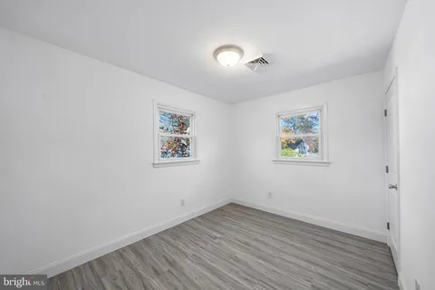 an empty room with wooden floor and window
