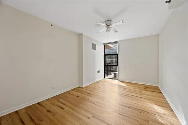a view of empty room with wooden floor and fan