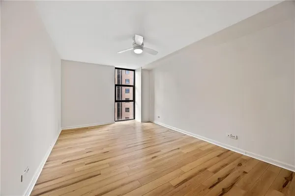 an empty room with windows and ceiling fan