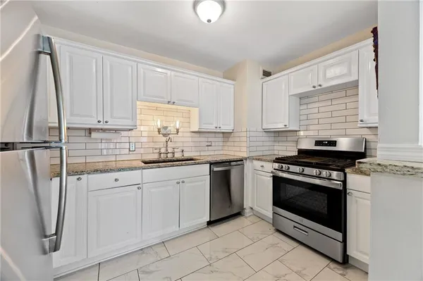 a kitchen with white cabinets a sink and appliances