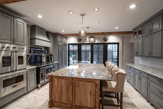 a kitchen with stainless steel appliances granite countertop a stove top oven a sink dishwasher a dining table and chairs with wooden floor